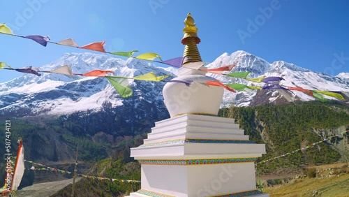 Parallax of Stupa with prayer flags waving in the wind and picturesque sunny Himalaya mountain peak views in the distance, Annapurna, Nepal photo