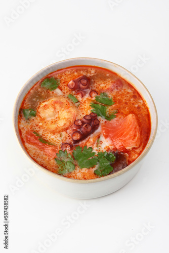 Soup with seafood and tomatoes. Soup with octopus, king prawns and red fish.Vertical photo.Isolated object. White background.