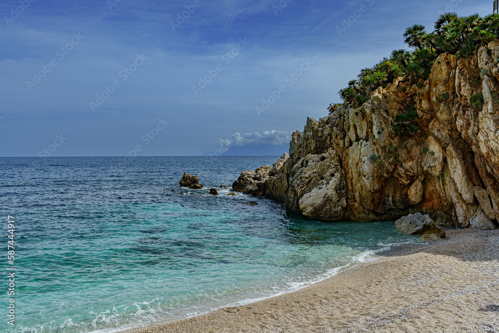 A beautiful view of the calm sea and the sandy beach surrounded by rocks A beautiful view of the calm sea and the sandy beach surrounded by rocks