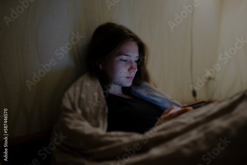 Woman uses her phone before bed