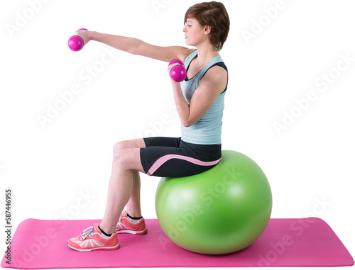 Pretty brunette exercising with dumbbells on fitness ball 