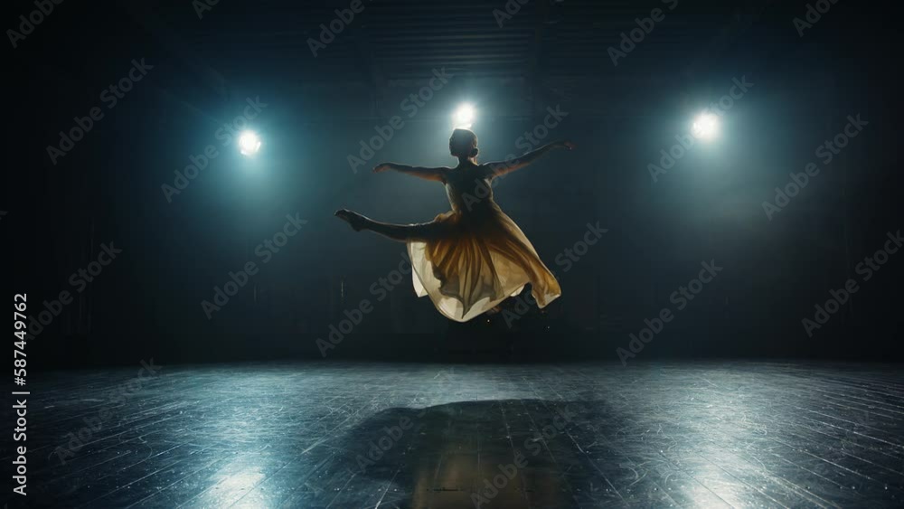 Young graceful classical ballet female dancer in tutu is performing choreography on stage. Ballerina makes difficult pirouette on stage