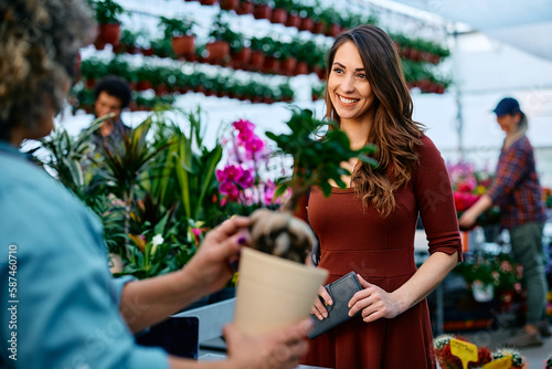 Canvas Print Happy woman buys flowers in garden center.