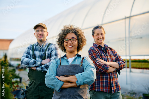 Foto Confident greenhouse owner and her workers looking at camera.