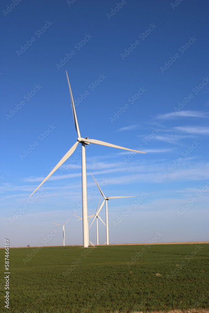 Vertical image of giant wind turbines in a field Vertical image of giant wind turbines in a field
