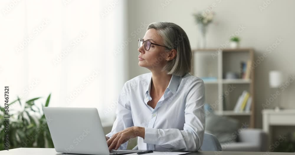 Focused middle-aged woman sit at desk, using laptop, looking pensive or concerned, learn new application, working on research project online on computer, do remote work, think about issue solution Focused middle-aged woman sit at desk, using laptop, looking pensive or concerned, learn new application, working on research project online on computer, do remote work, think about issue solution