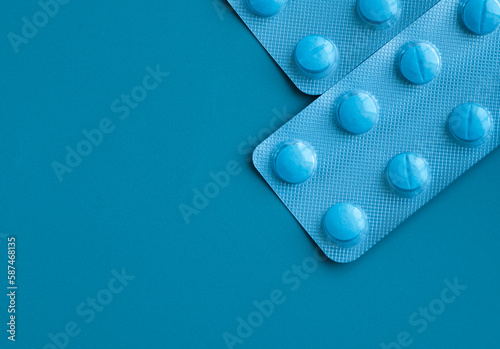 Two blisters of blue pills on a blue background. Blisters are located in the corner.
