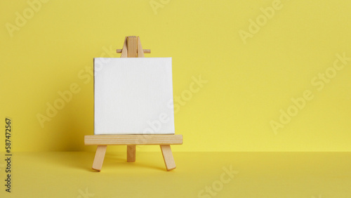 Mini painting on an easel on a yellow background. Directly