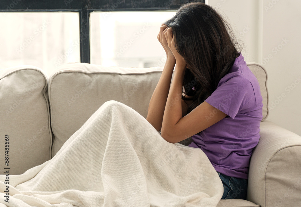 Negative thoughtful tired asian woman holding hand on head trouble sitting alone on sofa at home . Upset sad young girl crying lonely problem feeling break up or unwell sitting on couch at apartment. Negative thoughtful tired asian woman holding hand on head trouble sitting alone on sofa at home . Upset sad young girl crying lonely problem feeling break up or unwell sitting on couch at apartment.