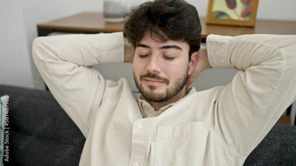 Young hispanic man relaxed with hands on head sitting on sofa at home Young hispanic man relaxed with hands on head sitting on sofa at home