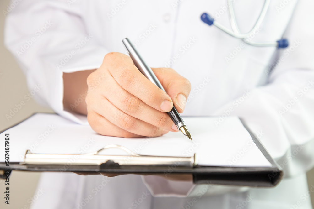 Cropped shot of an unrecognisable doctor writing notes in a folder in a modern hospital Cropped shot of an unrecognisable doctor writing notes in a folder in a modern hospital