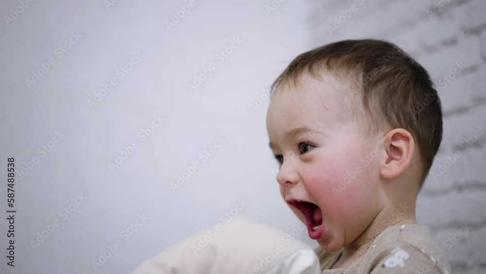 Smiling toddler boy with adorable rosy cheeks. Happy child plays with pillow and jumps up. Smiling toddler boy with adorable rosy cheeks. Happy child plays with pillow and jumps up.