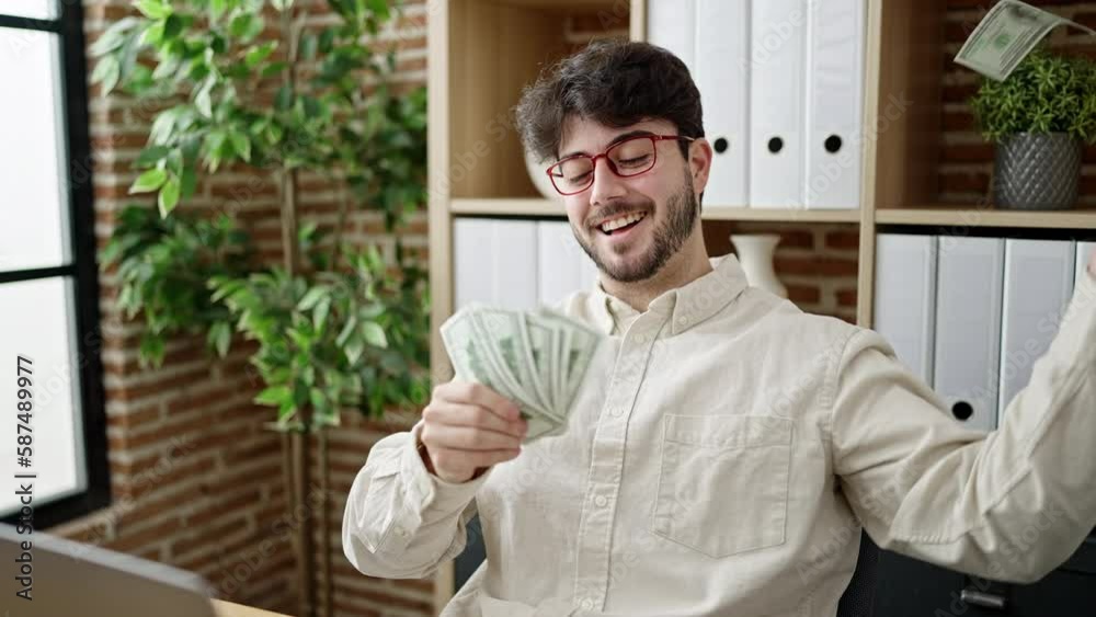 Young hispanic man business worker using laptop throwing dollars at office Young hispanic man business worker using laptop throwing dollars at office