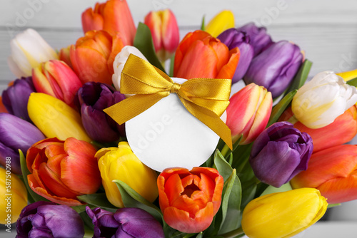 Bouquet of beautiful colorful tulips with blank card on white wooden background  closeup. Birthday celebration