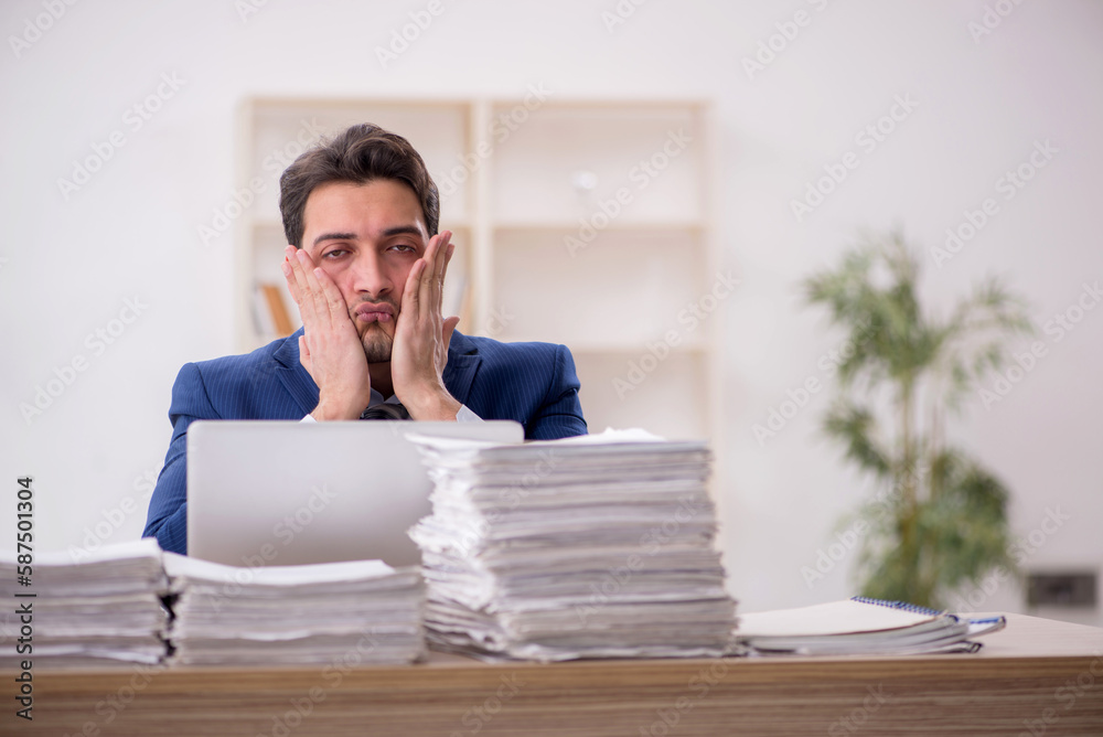 Young male employee and too much work in the office Young male employee and too much work in the office
