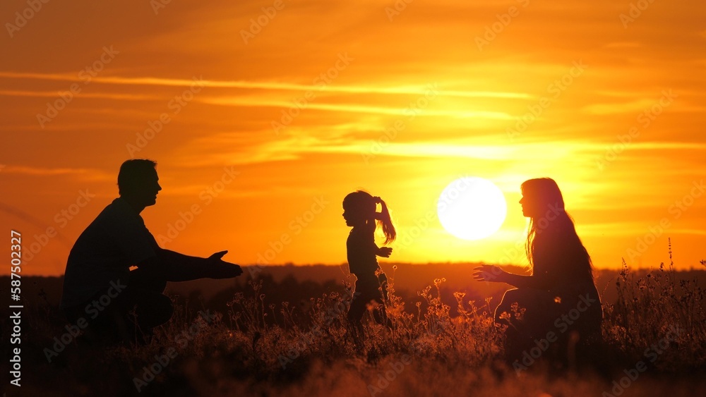 Child plays with parents. Kid runs from mom to dad, hugs and kisses his parents at sunset. Happy family walks in park with their daughter in sun. Father, mother, child, healthy family playing in field