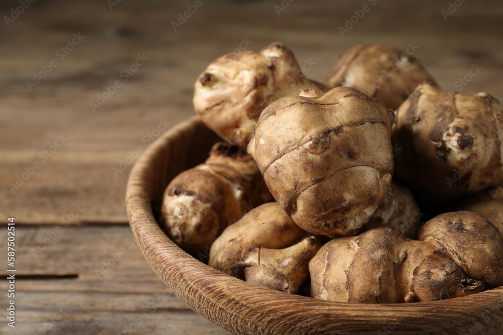 Bowl with fresh Jerusalem artichokes on wooden table, closeup Bowl with fresh Jerusalem artichokes on wooden table, closeup