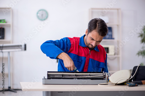 Young male repairman repairing air-conditioner © Elnur