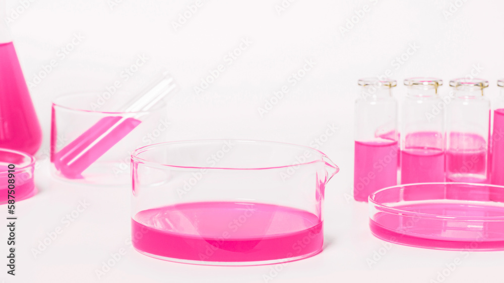 Bowl for a laboratory with a pink liquid. Against the background of laboratory glassware. Petri dishes, flasks, test tubes. On a white, light background.