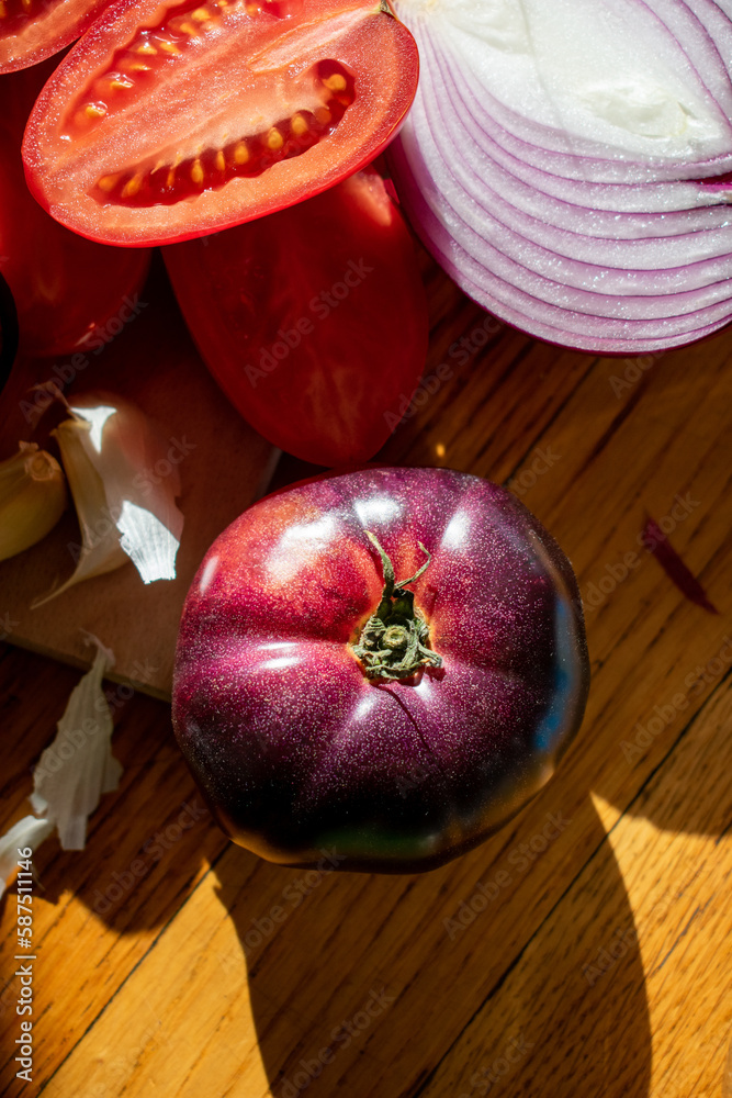 heirloom tomato and cut red onion peppers and garlic on a cutting board