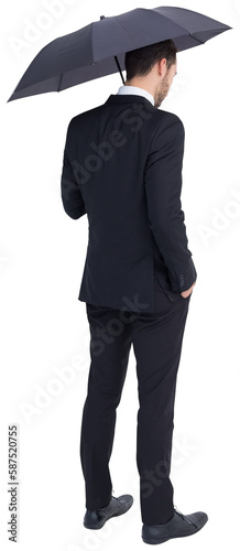 Thoughtful businessman under umbrella with hand in pocket
