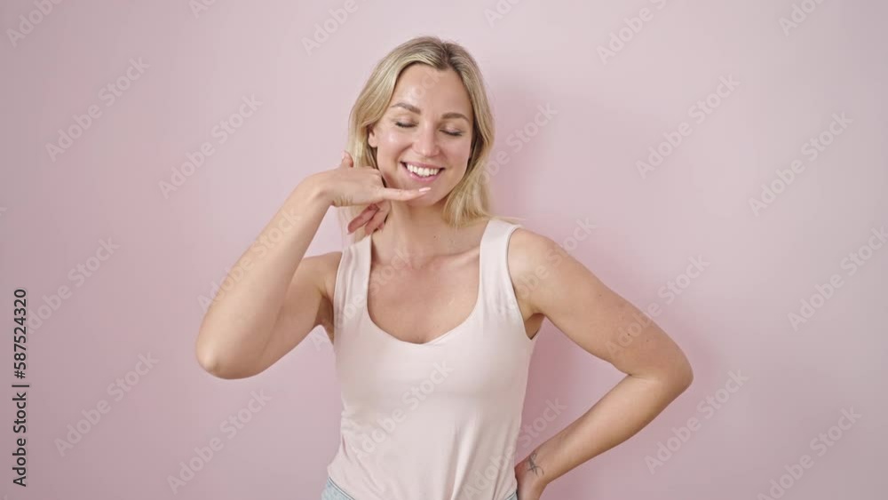 Young blonde woman smiling confident doing call me gesture with hand over isolated pink background Young blonde woman smiling confident doing call me gesture with hand over isolated pink background