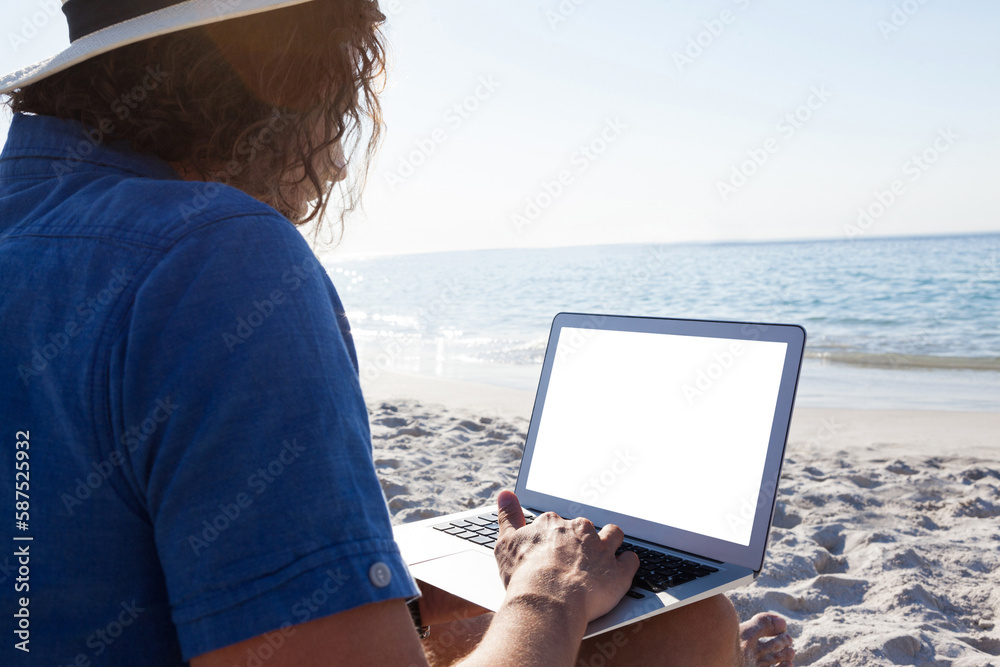 Man using laptop on the beach