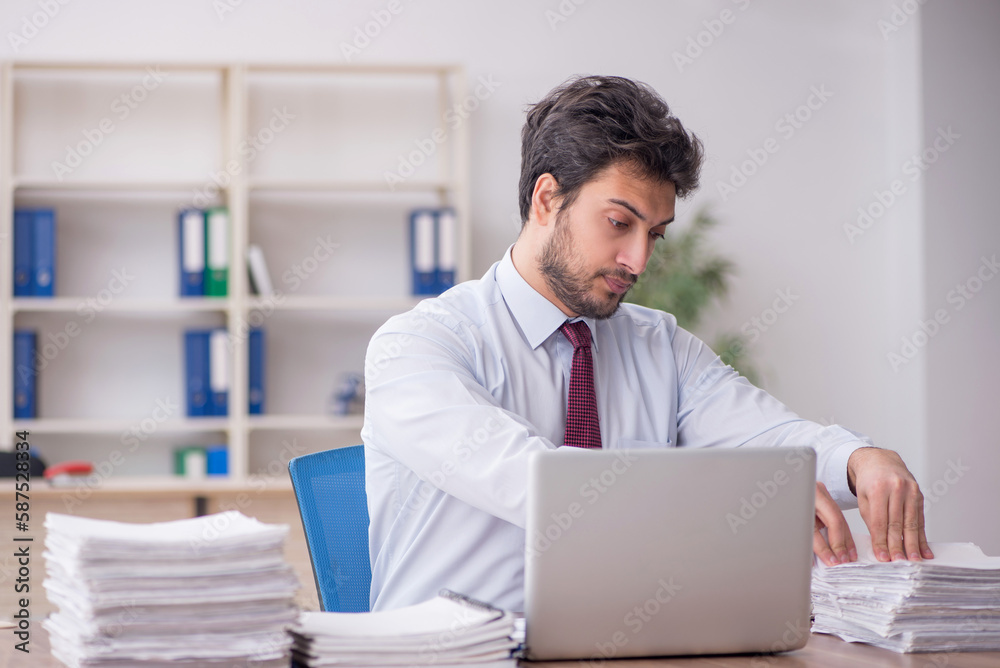 Young male employee and too much work in the office Young male employee and too much work in the office