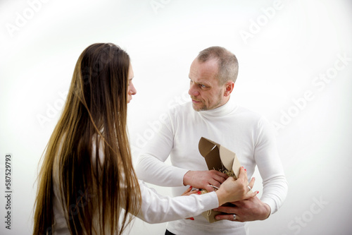 girl hits the man on the forehead trying to get a gift from the box the man gives coconut in packaging material girl closes man opens box white sweaters joke great funny newlyweds relationship photo