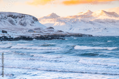 Snowy Mountains at Winter, Sunrise with Fluffy Clouds and Stormy Sea in Iceland. Landscape in North Europe Country. Atlantic Ocean Coast and Icelandic Fjords.
