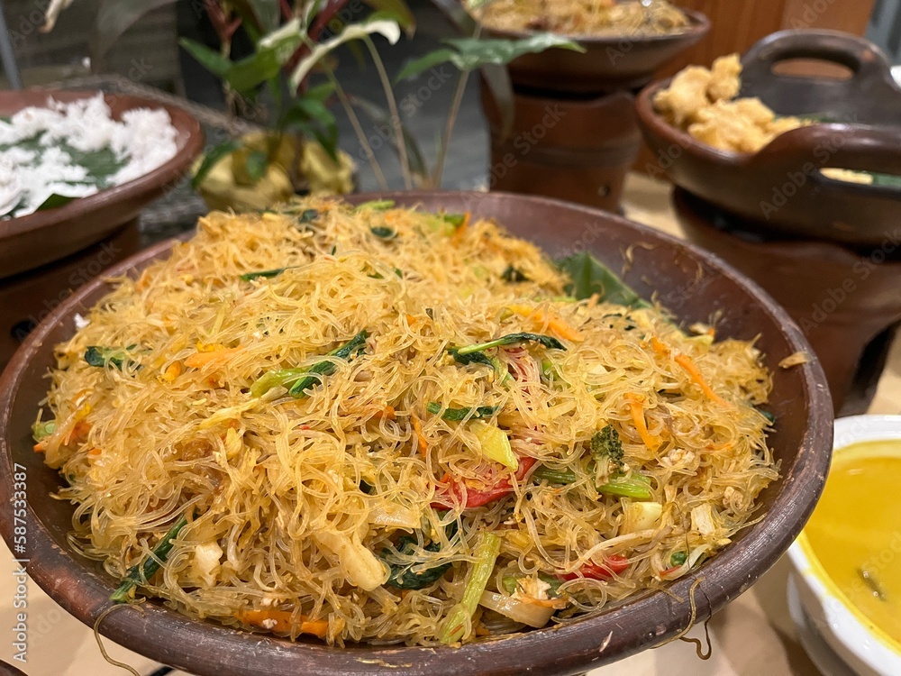 Big portion of fried vermicelli or rice noodle being served in a clay pot on a buffet table. Big portion of fried vermicelli or rice noodle being served in a clay pot on a buffet table.