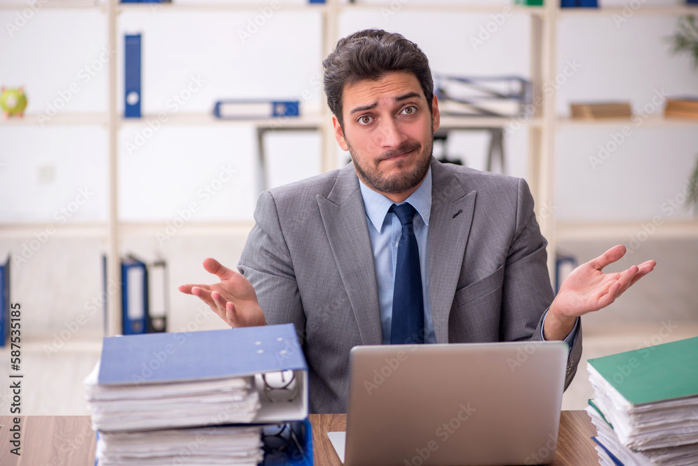 Young male employee and too much work in the office Young male employee and too much work in the office