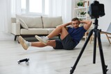Man athlete blogger records exercise training on the body at home on camera, sports blogger bodybuilder, the concept of health and beauty