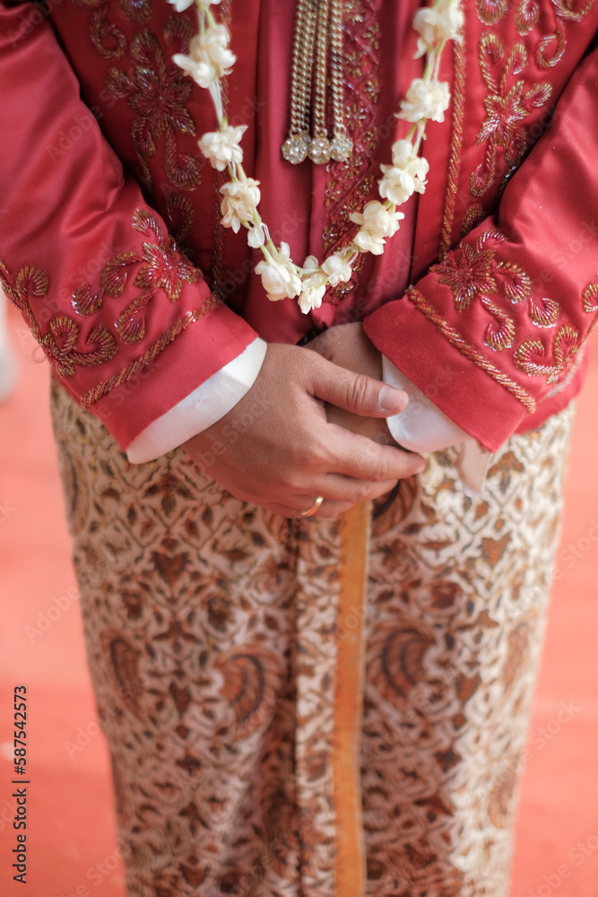 A bride wears a traditional dress with a flower design on the front.