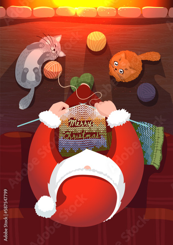 Santa claus knits a scarf with the inscription Merry Christmas at the fireplace with cute kittens. View from above.