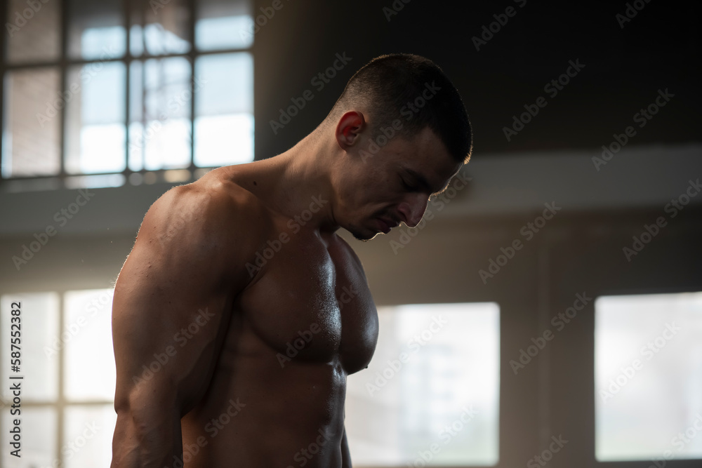 Obraz premium A young sexy athlete with perfect abs poses in the studio