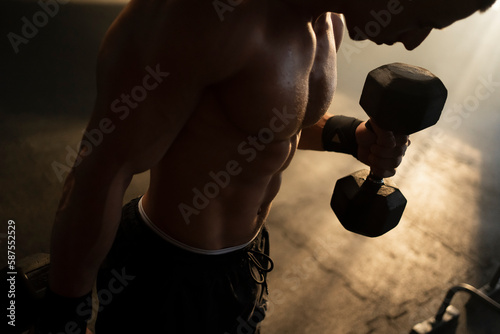 Foto Close-up view of a shirtless man with muscular body doing dumbbell curls in gym