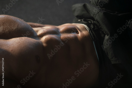 Fit young man with muscular body lying on floor and making abdominal exercises