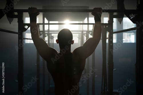 A male athlete training on a horizontal bar in the summer inside an abandoned warehouse