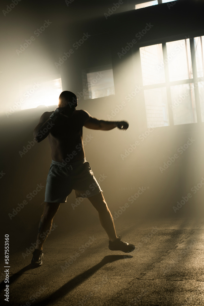 Cinematic shot of professional male boxer practicing shadow boxing in cross training workout space