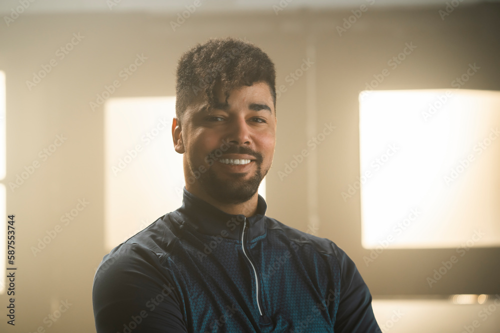 Close-up portrait view of a young man standing at gym, looking and smiling at camera Close-up portrait view of a young man standing at gym, looking and smiling at camera
