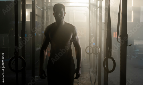 Athletic man standing behind the pull-up crossfit rings in the gym