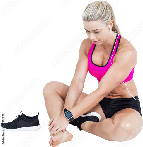 Injured female athlete sitting and touching ankle