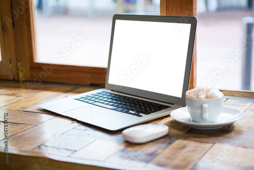 Laptop by coffee cup on table in cafe