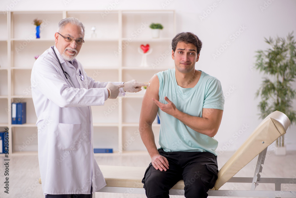 Fototapeta premium Young male patient visiting old male doctor in vaccination conce