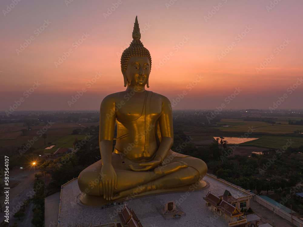 Obraz premium aerial view The moon was above the head of the biggest golden Buddha in the world..scenery red sky in twilight background. .golden big buddha is a popular landmark at wat Muang Ang Thong Thailand.