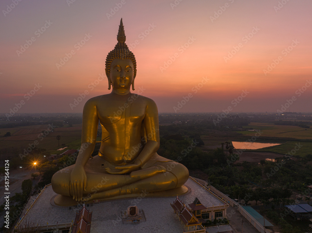 Obraz premium aerial view The moon was above the head of the biggest golden Buddha in the world..scenery red sky in twilight background. .golden big buddha is a popular landmark at wat Muang Ang Thong Thailand.