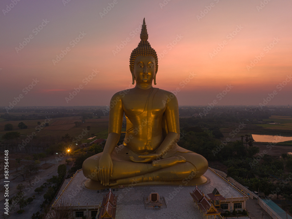 Obraz premium aerial view The moon was above the head of the biggest golden Buddha in the world..scenery red sky in twilight background. .golden big buddha is a popular landmark at wat Muang Ang Thong Thailand.