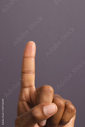 Hand of biracial man with outstretched forefinger, on grey background with copy space