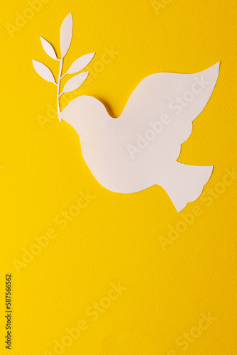 Close up of white dove with leaf and copy space on yellow background